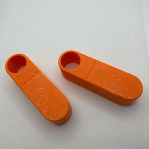 May include: Two orange, rectangular objects with rounded ends and a circular hole at one end. The word "Renegade" is printed on the side of each object. The objects have a textured surface and appear to be made of plastic.