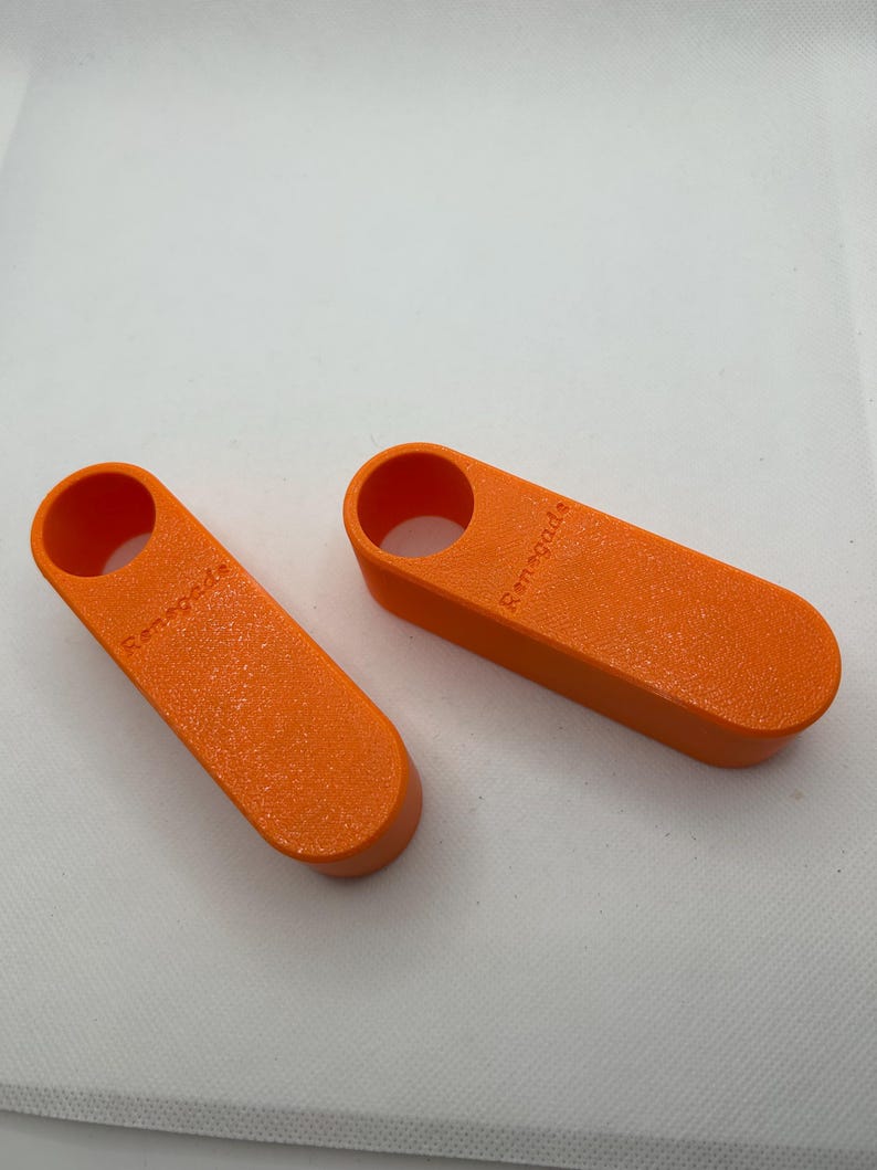 May include: Two orange, rectangular objects with rounded ends and a circular hole at one end. The word "Renegade" is printed on the side of each object. The objects have a textured surface and appear to be made of plastic.