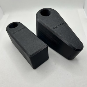 Puede incluir: Dos topes de puerta negros, uno m&aacute;s peque&ntilde;o y rectangular, el otro m&aacute;s grande e inclinado. Cada uno tiene la palabra "Renegade" impresa. Los topes de puerta est&aacute;n hechos de un material negro mate. El m&aacute;s grande mide unos 15 cm.