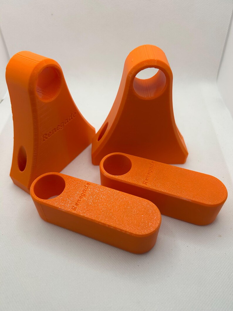 May include: Four bright orange 3D-printed objects. Two are tall with a circular opening at the top and a smaller hole on the side. The other two are rectangular with a circular opening. The word "Renegade" is printed on each object.