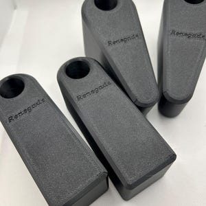 Puede incluir: Cuatro topes de puerta negros, rectangulares, con una parte superior redondeada. La palabra "Renegade" est&aacute; impresa en el lateral de cada uno. Est&aacute;n dispuestos sobre una superficie blanca.