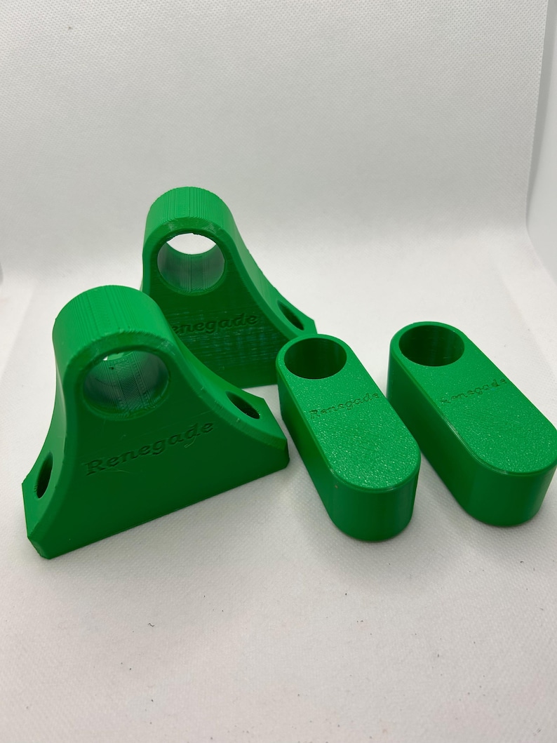 May include: Four bright green 3D-printed objects. Two are angled with a circular opening and the word "Renegade" printed on the side. The other two are rectangular with rounded ends and the word "Renegade" printed on the side.