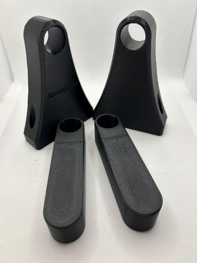 May include: Four black 3D-printed objects. Two are tall with a circular opening at the top and a smaller hole on the side. Two are rectangular with rounded ends. The word "Renegade" is printed on the objects.