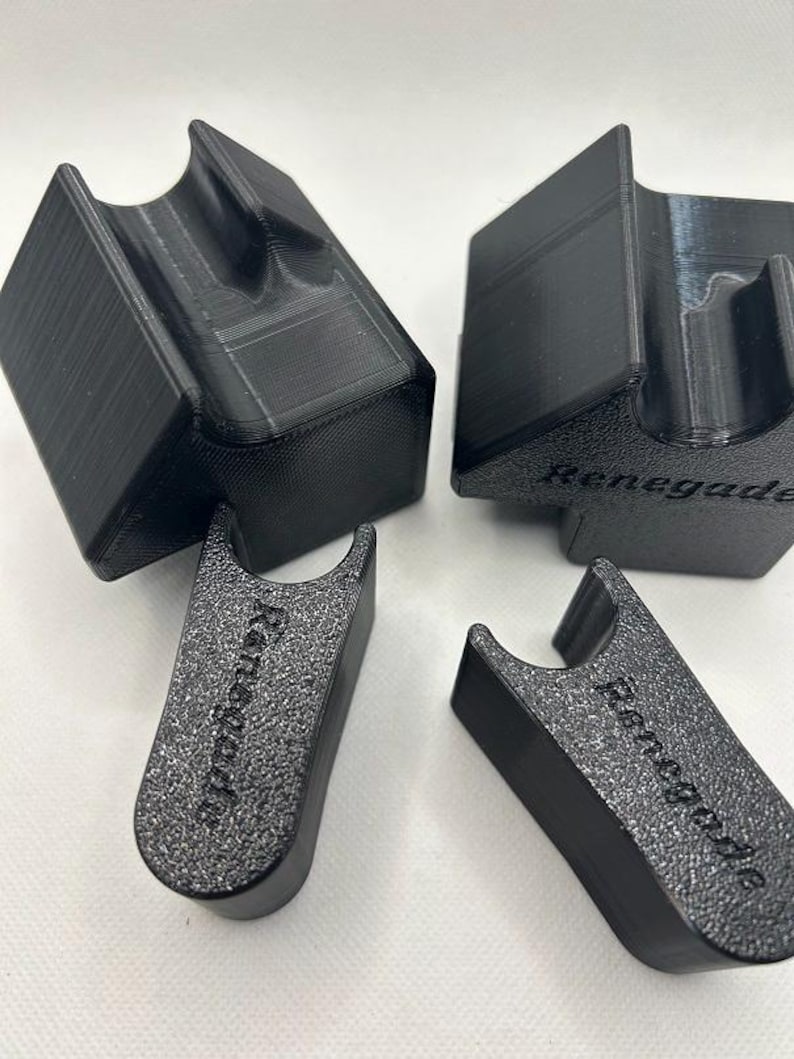 May include: Four black 3D-printed holders. Two are rectangular with a curved top, and two are smaller with the word "Renegade" printed on them. The holders are designed to hold an item.