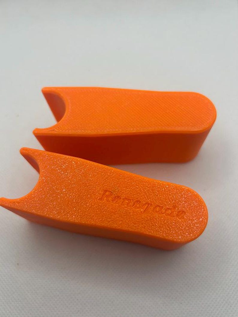 May include: Two bright orange, rectangular objects with a textured surface and a curved cutout on one end. The word "Renegade" is embossed on one of the objects. The objects are set against a white background.