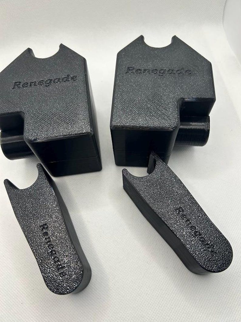 May include: Four black, textured, 3D-printed objects. Two are rectangular with a curved top and the word "Renegade" printed on them. The other two are larger, with a similar texture and the word "Renegade" printed on them.