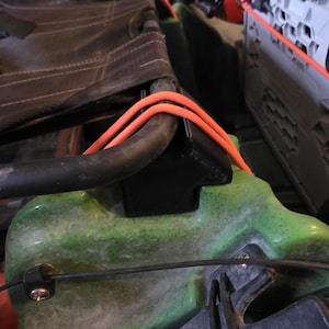 May include: Close-up of a kayak seat with orange rope and black hardware. The seat is black and attached to a green kayak. The image shows the details of the seat's construction and the kayak's components.