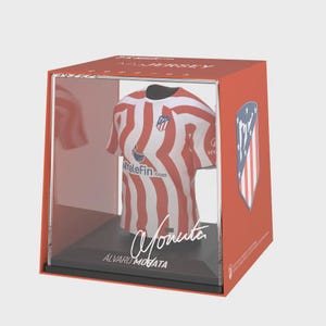 May include: A red and white striped soccer jersey displayed in a clear box with a red exterior. The jersey has a sponsor logo and the name "Morata" is visible. A team logo is on the box.