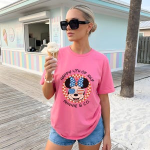 Pink t-shirt with Minnie Mouse in patriotic sunglasses, worn by a woman holding an ice cream cone.