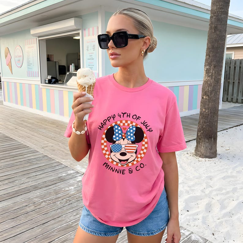 Pink t-shirt with Minnie Mouse in patriotic sunglasses, worn by a woman holding an ice cream cone.
