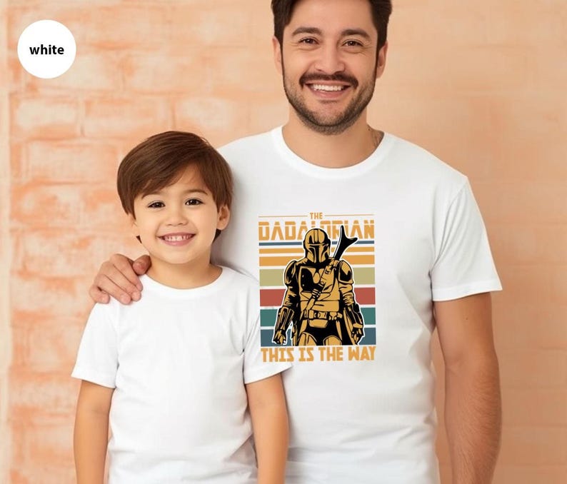 A young boy and an adult man wearing white t-shirts with a graphic of a character from the Star Wars franchise.