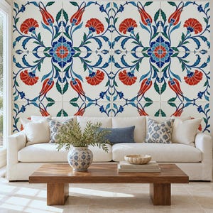 May include: A white sofa with two patterned throw pillows and one solid blue pillow, positioned in front of a wall covered in square tiles featuring a repeating floral pattern in red, blue, and green on a white background.