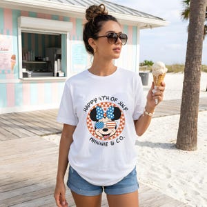 White t-shirt with Minnie Mouse in patriotic sunglasses, worn by a woman holding ice cream.