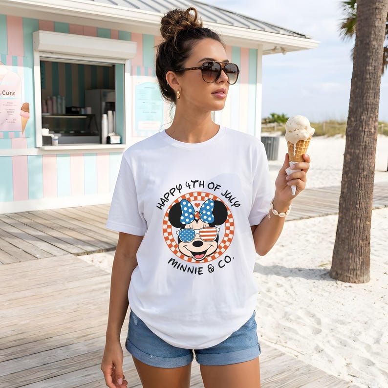 White t-shirt with Minnie Mouse in patriotic sunglasses, worn by a woman holding ice cream.