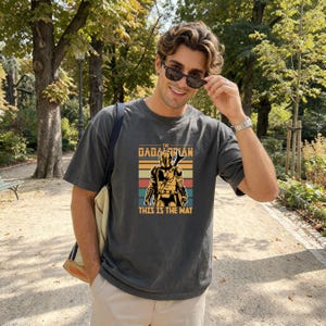 A man wearing a t-shirt with a graphic of a character from the Star Wars franchise, smiling and posing outdoors in a park.