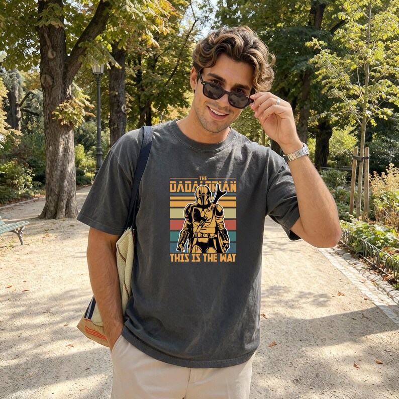 A man wearing a t-shirt with a graphic of a character from the Star Wars franchise, smiling and posing outdoors in a park.