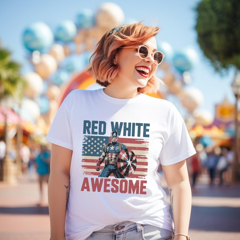 Smiling woman in a white t-shirt with a Captain America design and "RED WHITE AWESOME" text, outdoors.