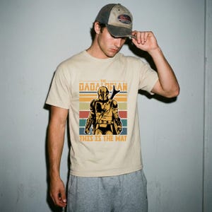 A man wearing a t-shirt with a graphic of a character from the Star Wars franchise and the text "This is the way" printed on it.