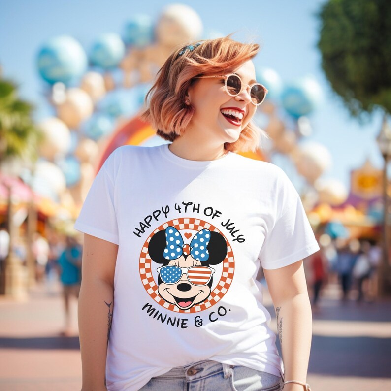 White t-shirt with "Happy 4th of July Minnie & Co." design, worn by a smiling girl outdoors.