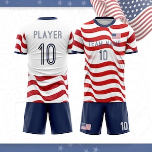 May include: A sports uniform set featuring a jersey and shorts with a red, white, and blue wavy flag pattern. The jersey displays the text TEAM NAME and PLAYER with the number 10. The shorts feature a small American flag and the number 10.