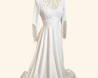 Puede incluir: Un vestido blanco largo hasta el suelo con mangas largas con ribete de encaje, cuello alto y un panel transparente en el canesú adornado con intrincados bordados blancos. El corpiño es entallado con una cintura definida y una falda larga con encaje.