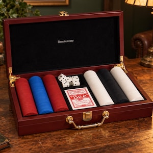 May include: A mahogany-colored wooden poker set case with gold-tone hardware and a black interior featuring the Brookstone logo. The set includes stacks of red, blue, white, and black poker chips, five white dice, and a deck of Bee playing cards.