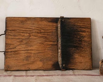 Tabla de cortar antigua de madera rústica con mango de hierro.