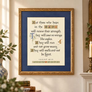 May include: A framed wall art piece featuring the text of Isaiah 40:31 in a calligraphic font. The print is set against a cream background with decorative floral accents, enclosed in a deep blue mat and an ornate, textured gold-colored frame.