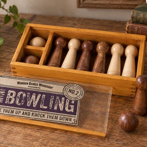 May include: A wooden mini bowling game set featuring a rectangular storage box with compartments, six wooden pins in light and dark brown tones, and two wooden balls. The clear sliding lid displays the text: WOODEN GAMES WORKSHOP PRESENTS MINI BOWLING NO.2 LINE THEM UP AND KNOCK THEM DOWN.