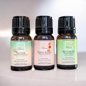 Può includere: Tre bottiglie di oli essenziali con tappi neri ed etichette. Le etichette recitano "Nut Job (Toasted Pistachio)", "Peach, Please (Yogurt Parfait)" e "Key Lime Pie (Citrus Cream)". Ogni bottiglia contiene 10 ml di olio, fatto a mano in Canada.