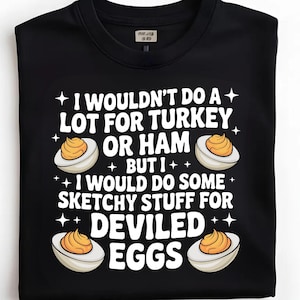 Puede incluir: Sudadera negra con el texto blanco "I WOULDN'T DO A LOT FOR TURKEY OR HAM BUT I WOULD DO SOME SKETCHY STUFF FOR DEVILED EGGS". El diseño incluye ilustraciones de huevos rellenos.