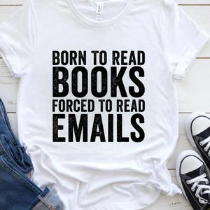 Peut inclure: T-shirt blanc avec l'inscription noire "BORN TO READ BOOKS FORCED TO READ EMAILS". Le t-shirt est associé à un jean bleu et des baskets noires et blanches.