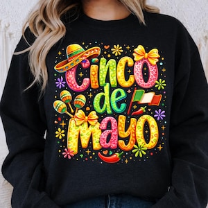 Può includere: Felpa nera con un colorato design del Cinco de Mayo. Il design include un sombrero, maracas, le parole "Cinco de Mayo", una bandiera messicana, peperoncini e accenti floreali.