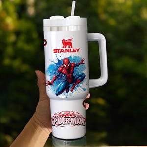 Puede incluir: Vaso Stanley blanco con un dise&ntilde;o de Spider-Man. Tiene un asa, una tapa blanca con pajita y el logotipo "STANLEY". La parte inferior del vaso tiene el texto "MARVEL ULTIMATE SPIDER-MAN".