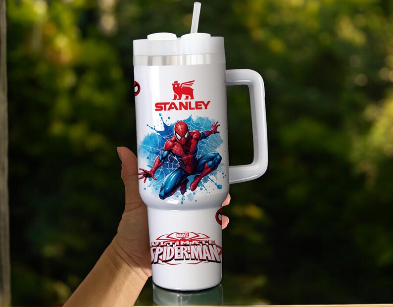 Puede incluir: Vaso Stanley blanco con un dise&ntilde;o de Spider-Man. Tiene un asa, una tapa blanca con pajita y el logotipo "STANLEY". La parte inferior del vaso tiene el texto "MARVEL ULTIMATE SPIDER-MAN".