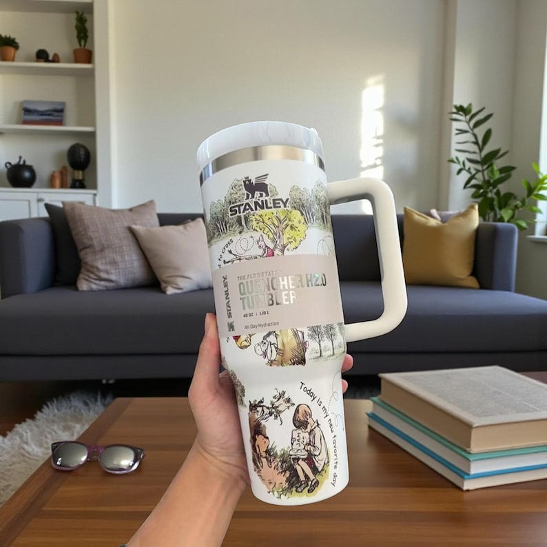 May include: White Stanley Quencher H2.0 tumbler with a large handle. The tumbler features illustrations and text, including "Stanley" and "Today is my new favorite day." It holds 40 oz (1.18 L).