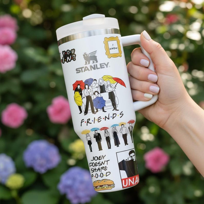 Puede incluir: Taza de viaje Stanley blanca con gr&aacute;ficos de la serie de televisi&oacute;n Friends. La taza tiene un asa y una tapa blancas y est&aacute; decorada con im&aacute;genes de los personajes, citas y logotipos del programa.