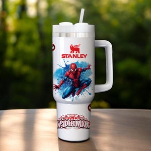 Puede incluir: Vaso Stanley blanco con un dise&ntilde;o de Spider-Man. El vaso tiene un asa, una tapa blanca con pajita y el logotipo de Marvel Ultimate Spider-Man. El dise&ntilde;o incluye una ilustraci&oacute;n de Spider-Man rojo y azul sobre un fondo de salpicaduras azules.
