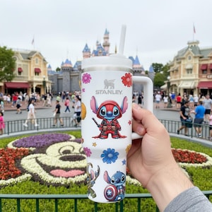 May include: A white ceramic mug with a black handle and the text "But First, Coffee" in a bold, black font. The mug is set against a blurred background, highlighting its simple design.