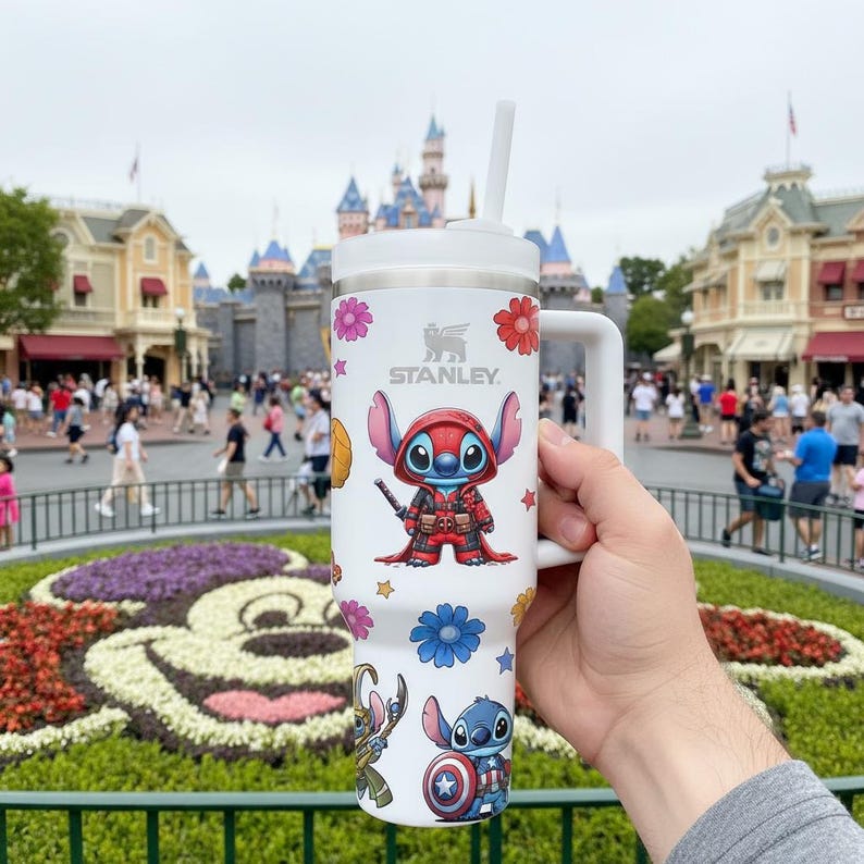 May include: A white ceramic mug with a black handle and the text "But First, Coffee" in a bold, black font. The mug is set against a blurred background, highlighting its simple design.