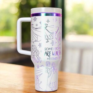 May include: White travel mug with a handle, featuring illustrations of characters and snowflakes. The mug has a white lid and handle, with a purple and silver band. The text "SOME PEOPLE ARE WORTH MELTING FOR" is printed on the side.