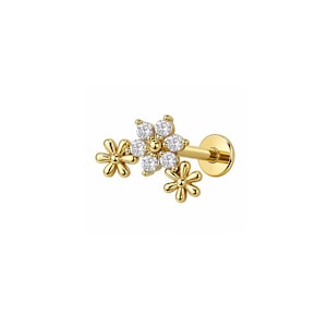 Könnte beinhalten: Ein goldfarbener Ohrstecker mit flacher Rückseite, bestehend aus einem zentralen Blumenmotiv mit sechs klaren runden Steinen, flankiert von zwei kleineren, schlichten goldfarbenen Blumenformen, befestigt an einem geraden Stift mit runder Scheibe.