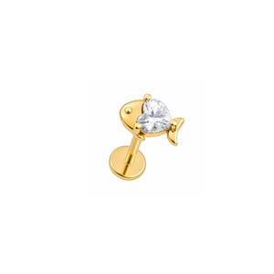 May include: A gold-toned flat back stud earring featuring a fish-shaped design. The fish body is crafted from polished gold-tone metal, while the head is set with a single, clear, heart-shaped gemstone that catches the light.