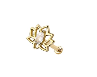 Puede incluir: Un pendiente de botón dorado con un diseño de flor de loto. La flor tiene un diseño calado con una piedra preciosa transparente en forma de pera en el centro. El poste del pendiente también es dorado.