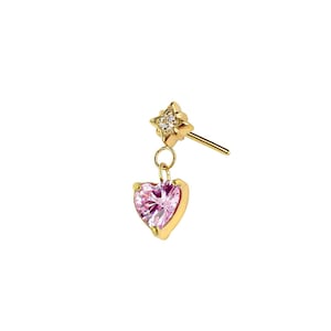 Puede incluir: Pendiente dorado con un colgante de piedra preciosa en forma de corazón rosa. El pendiente también tiene un pequeño perno en forma de estrella con piedras preciosas transparentes. Diseñado para orejas perforadas.