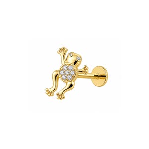 May include: A gold-toned stud earring featuring a frog-shaped design. The frog's body is circular and encrusted with small, clear, sparkling stones, while its head, arms, and legs are smooth gold. The earring includes a flat, circular back post.