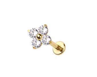 Könnte beinhalten: Ein goldfarbener Lippenpiercing-Stecker mit einem vierblättrigen Blumenmuster. Jedes Blütenblatt besteht aus einem klaren, rund geschliffenen Edelstein. Die Mitte der Blume ist eine kleine, goldfarbene Kugel. Der Stecker hat eine flache, runde Rückseite.