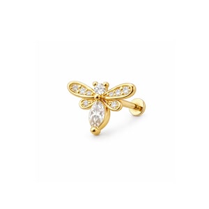 May include: A gold-colored bee-shaped earring with a post. The bee has two wings with small, round, clear stones and a larger, marquise-cut stone for the body. The earring is designed for a single ear piercing.