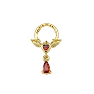 May include: A gold-toned hoop earring featuring a central heart-shaped red gemstone flanked by two small wings. A teardrop-shaped red gemstone hangs from the bottom of the heart. The piece is constructed with a hinged closure mechanism.