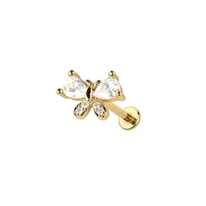 May include: A gold-colored butterfly-shaped earring with clear, heart-shaped and round-cut gemstones. The earring has a flat back and a post for piercing. The butterfly design features two larger heart-shaped stones and smaller round stones.